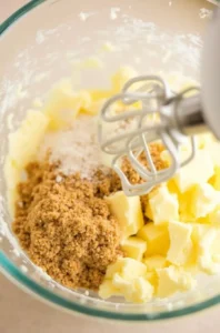 Creaming butter and sugar in a glass mixing bowl with a hand mixer until light and fluffy for banana bread chocolate chip cookies.